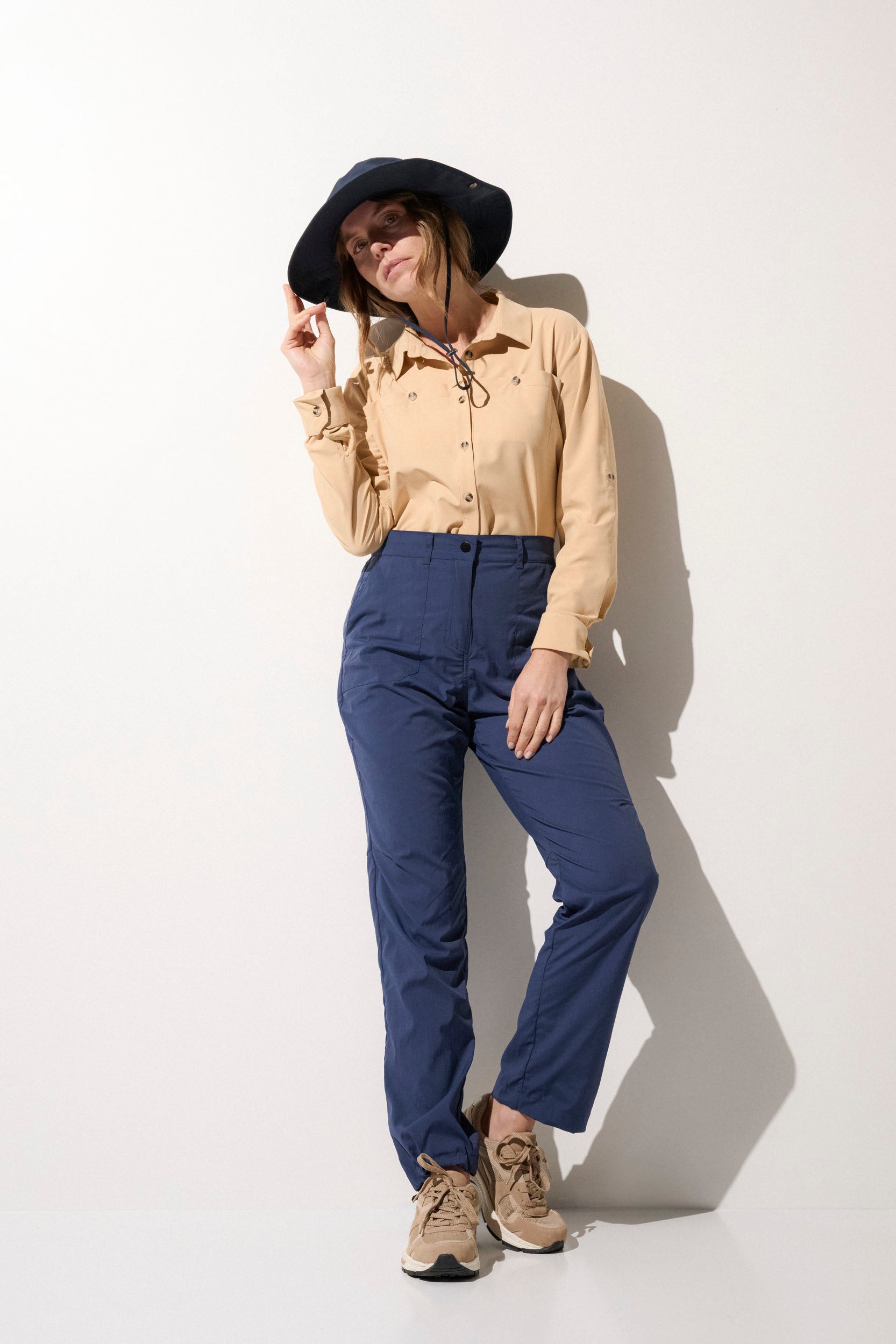 Femme portant un chapeau anti-UV noir et une chemise légère beige, idéale pour les activités en extérieur.