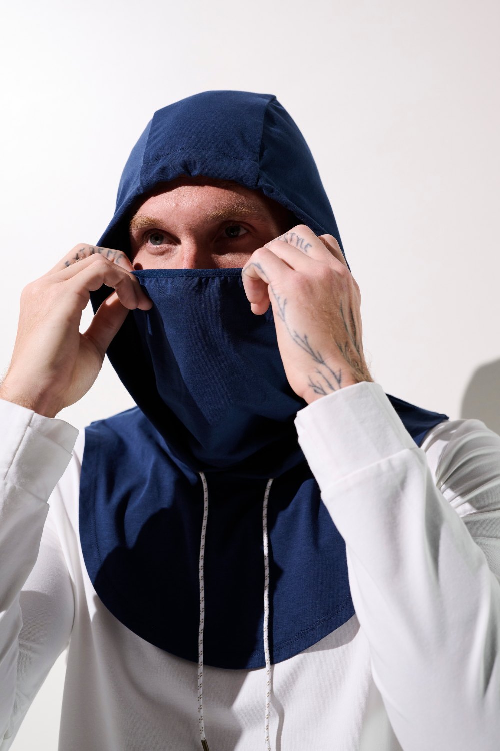 Capuche anti-UV - Mojave, homme ajustant sa capuche bleue UPF 50+ pour protection solaire optimale.