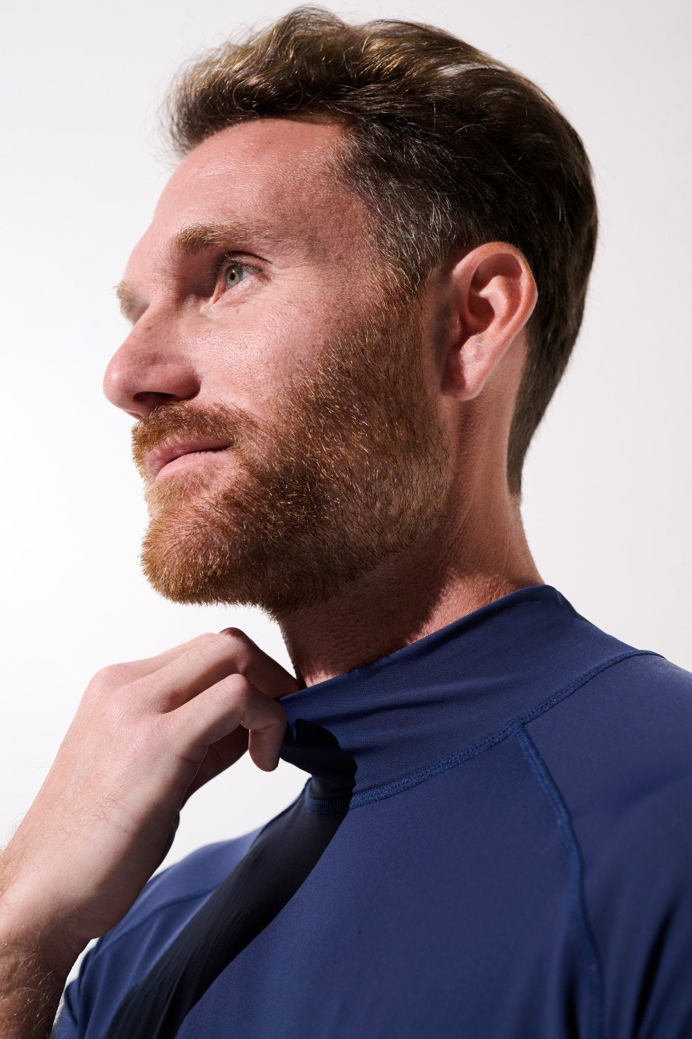 Homme ajustant son T-shirt de bain anti-UV - Malibu, bleu, UPF 50+ pour protection solaire efficace.