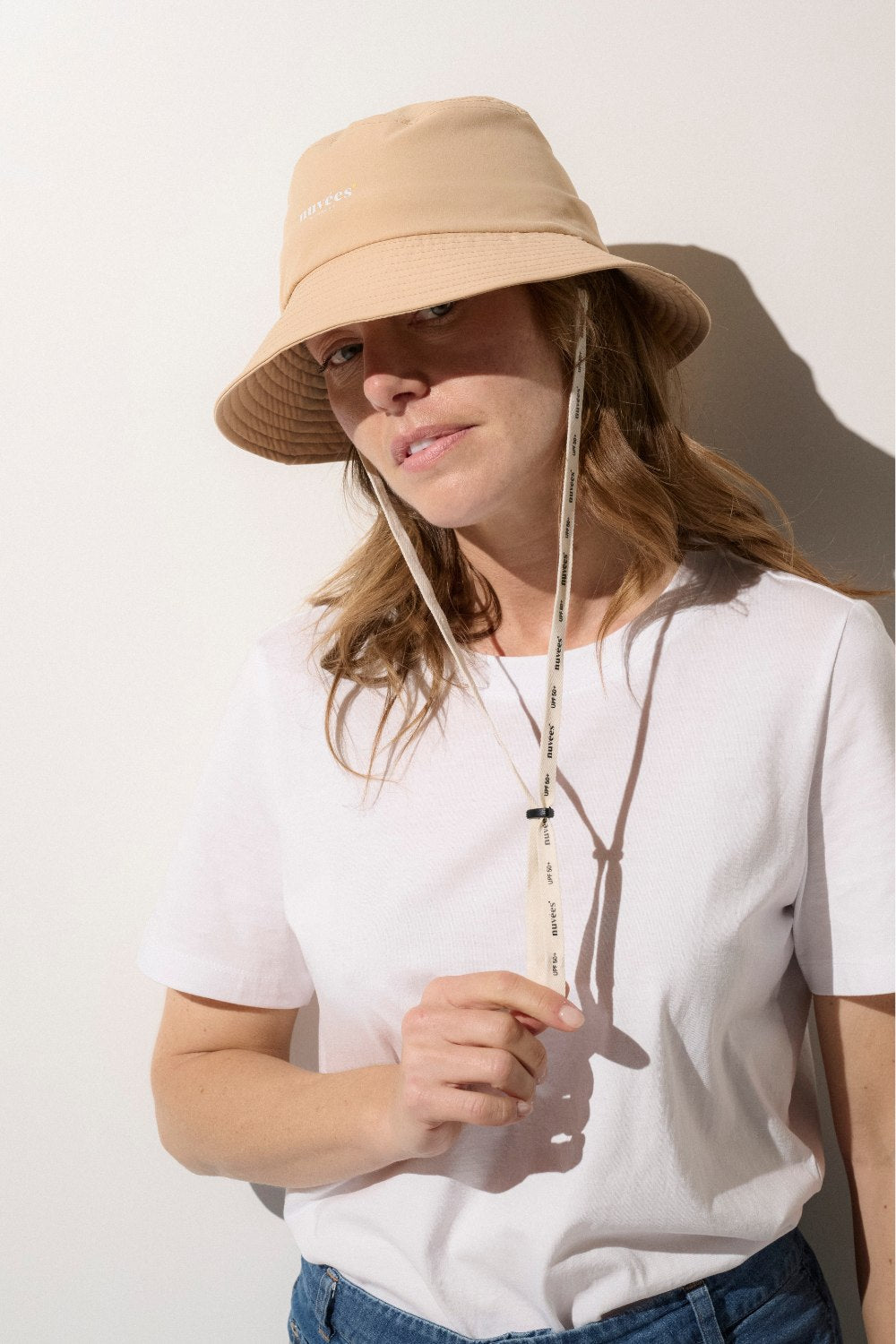 Femme portant un bob anti-UV beige, idéal pour les activités de plein air.