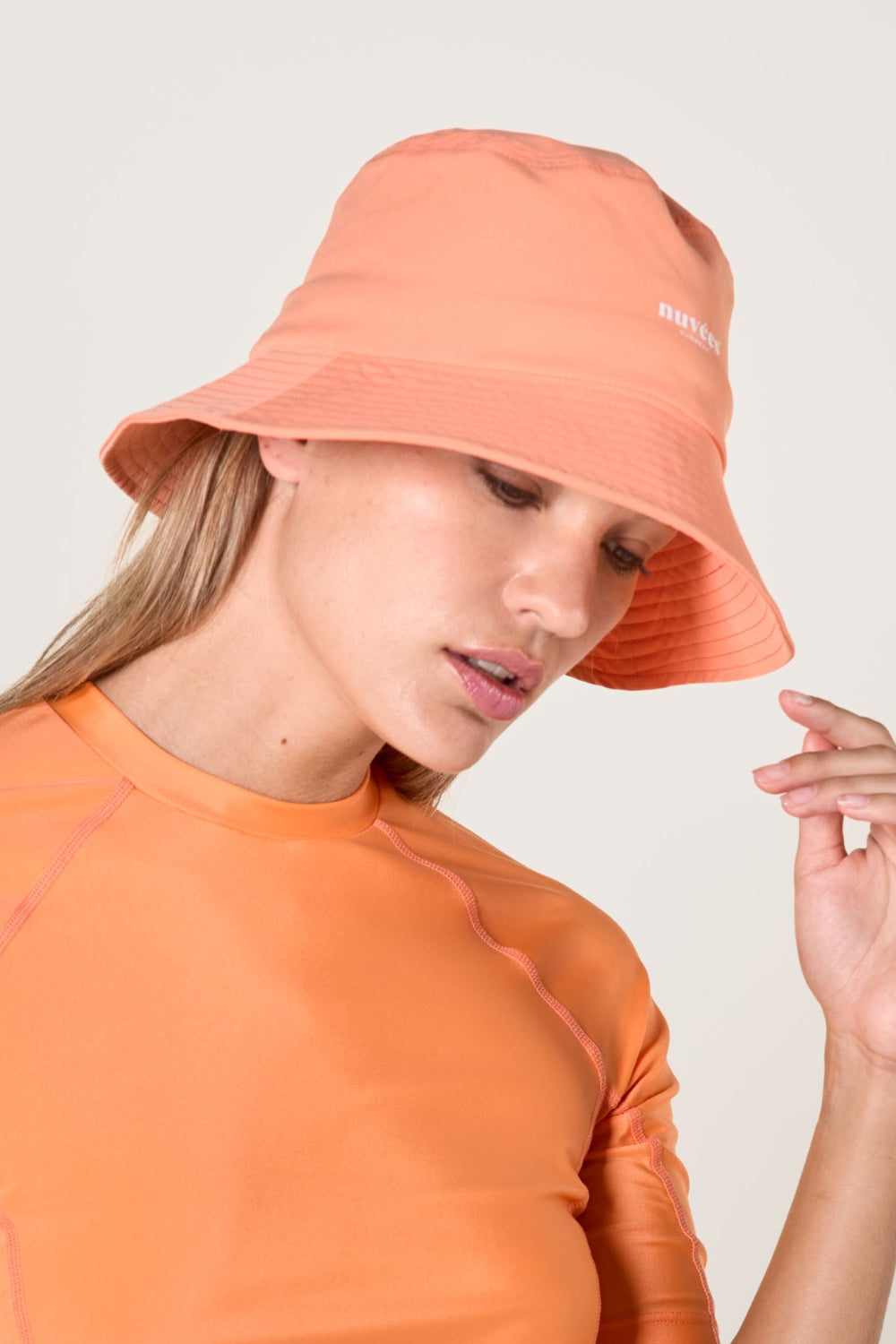 Femme portant un bob anti-UV couleur saumon, idéal pour se protéger des UV au quotidien.