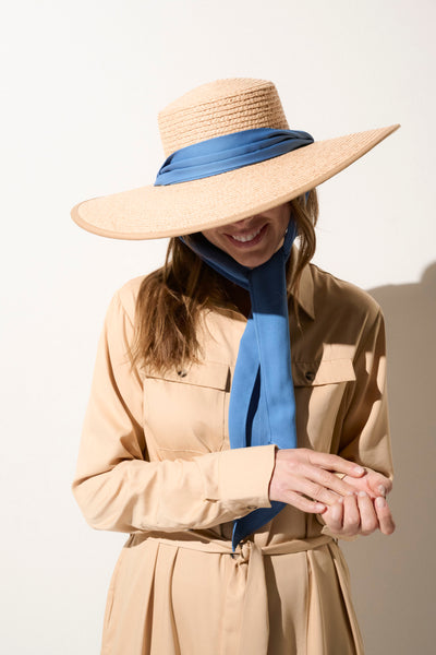 Chapeau anti-UV en paille beige avec un ruban bleu, offrant protection solaire efficace et style estivale pour femme.