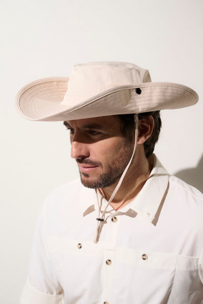 Chapeau anti-UV élégant beige UPF 50+ porté par un homme pour randonnées en plein air, offrant protection solaire.