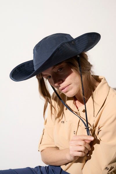 Chapeau anti-UV bleu marine UPF50+ pour femme, idéal pour randonnées et protections solaires.