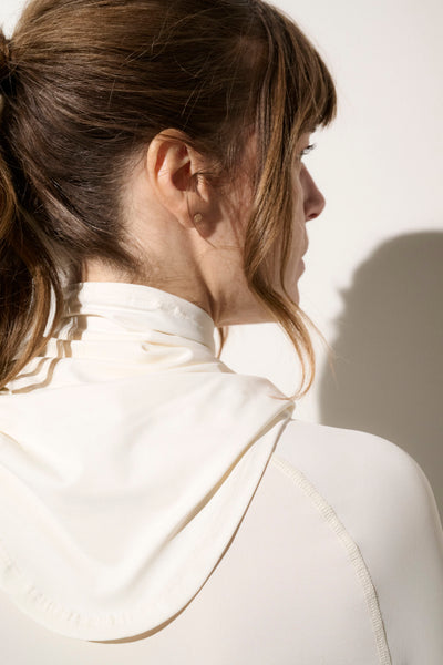 Femme portant un tour de cou anti-UV blanc UPF 50+, tissu léger et respirant, idéal pour activités en plein air.