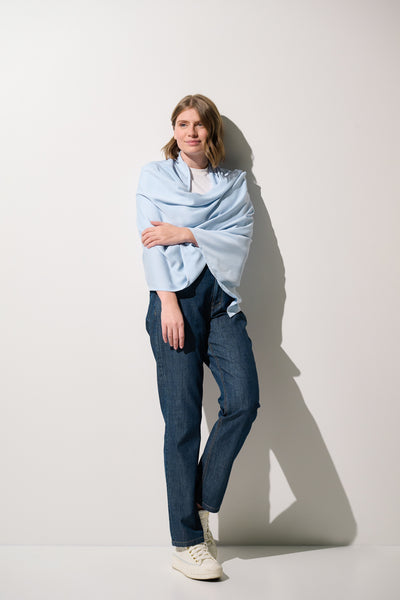 Étole anti-UV - Positano en bleu clair portée par une femme, offrant une élégante protection solaire UPF 50+.