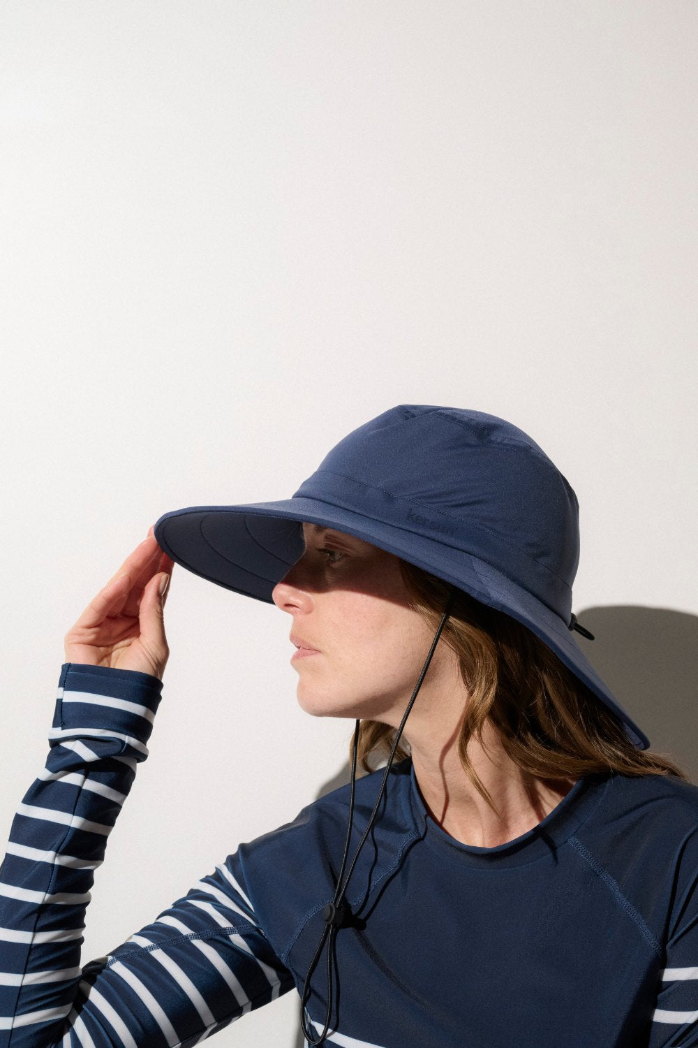 Chapeau de bain anti-UV bleu marine UPF 50+ porté par une femme, idéal pour se protéger du soleil lors d'activités en extérieur.