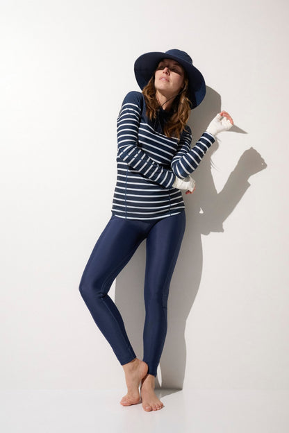 Femme portant un chapeau de bain anti-UV et une veste rayée UPF 50+, idéale pour se protéger au soleil.