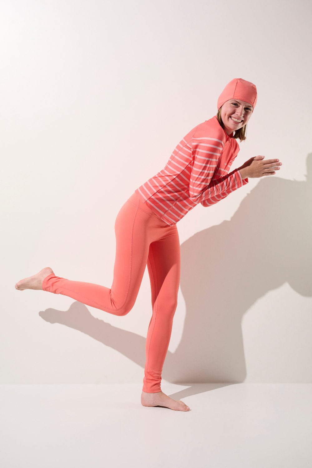 Bonnet de bain anti-UV - Pacific, femme en tenue sport anti-UV rose, UPF 50+, prête pour la baignade.