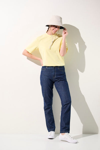 T-shirt anti-UV jaune UPF 50+ pour femme, porté avec un chapeau, idéal pour une journée ensoleillée.