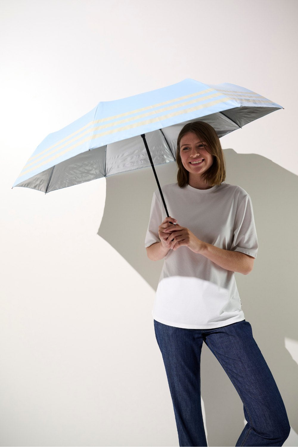 Ombrelle anti-UV bleue UPF 50+ tenue par une femme, parfaite pour se protéger du soleil lors de ses activités extérieures.