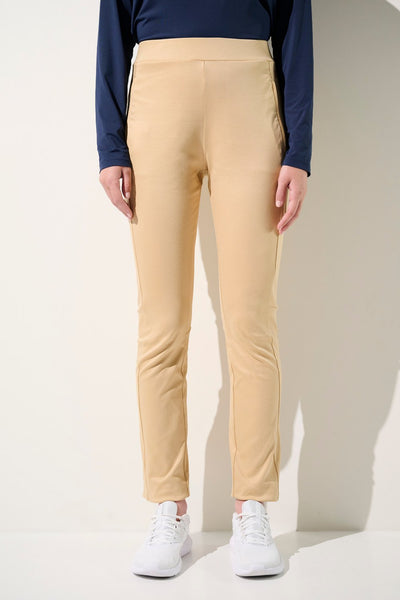 Pantalon anti-UV beige pour femme, léger et confortable, offrant une protection solaire UPF 50+, porté avec des chaussures blanches.