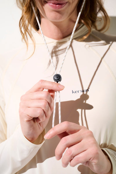 Femme portant un pull anti-UV beige de Ker Sun, ajustement avec cordon, idéal pour activités extérieures.
