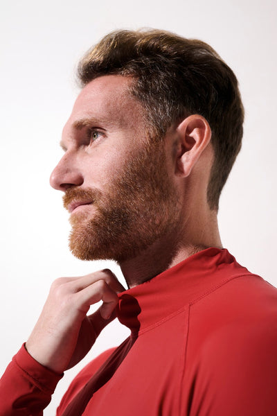 Homme portant un t-shirt de bain anti-UV rouge UPF 50+, idéal pour les activités aquatiques et la protection solaire.