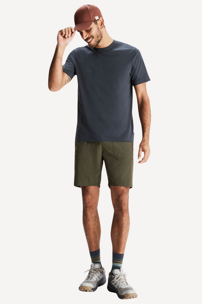 Homme en short anti-UV vert et t-shirt sombre, idéal pour randonnée, protection solaire UPF 50+.